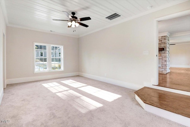 carpeted spare room featuring baseboards, visible vents, ceiling fan, and crown molding