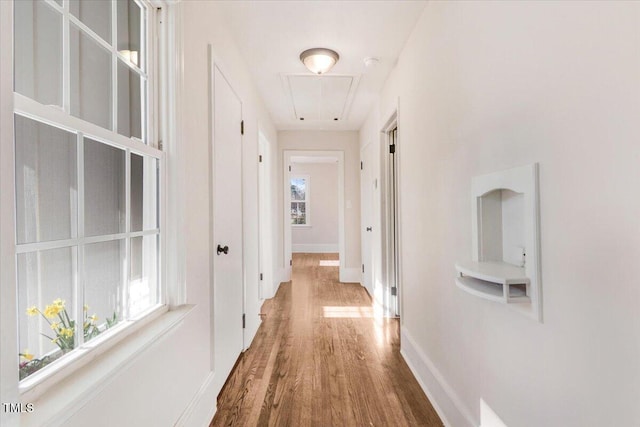 corridor with attic access, baseboards, and wood finished floors