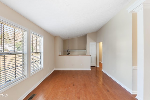 unfurnished living room featuring lofted ceiling, visible vents, a textured ceiling, wood finished floors, and baseboards