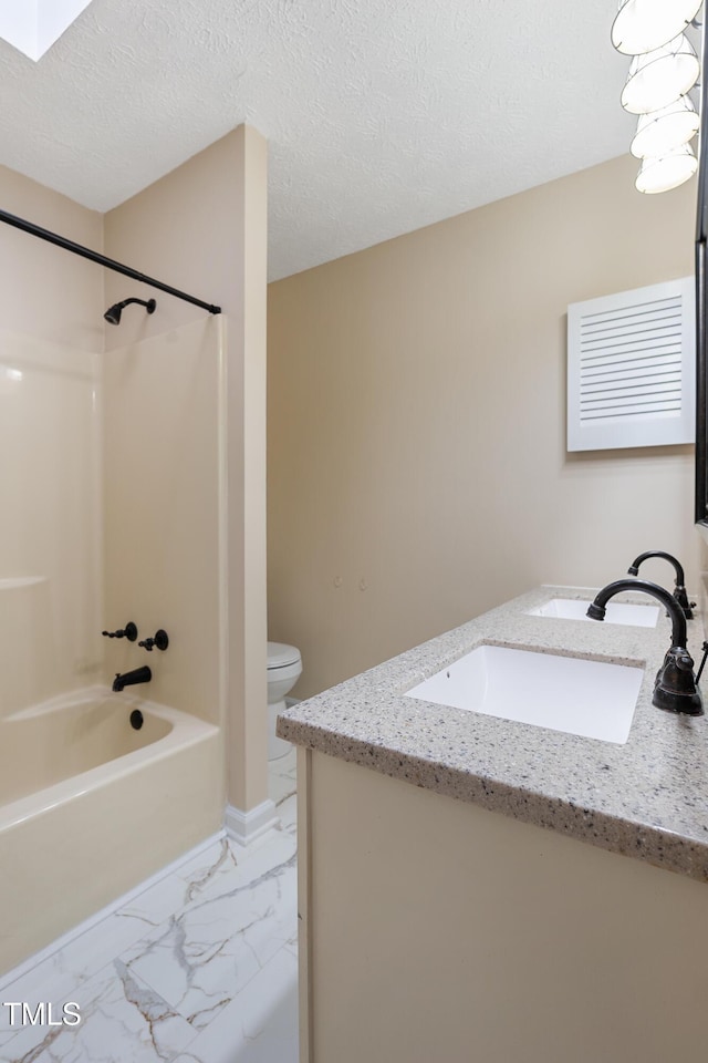 full bathroom with marble finish floor, a textured ceiling, toilet, and vanity