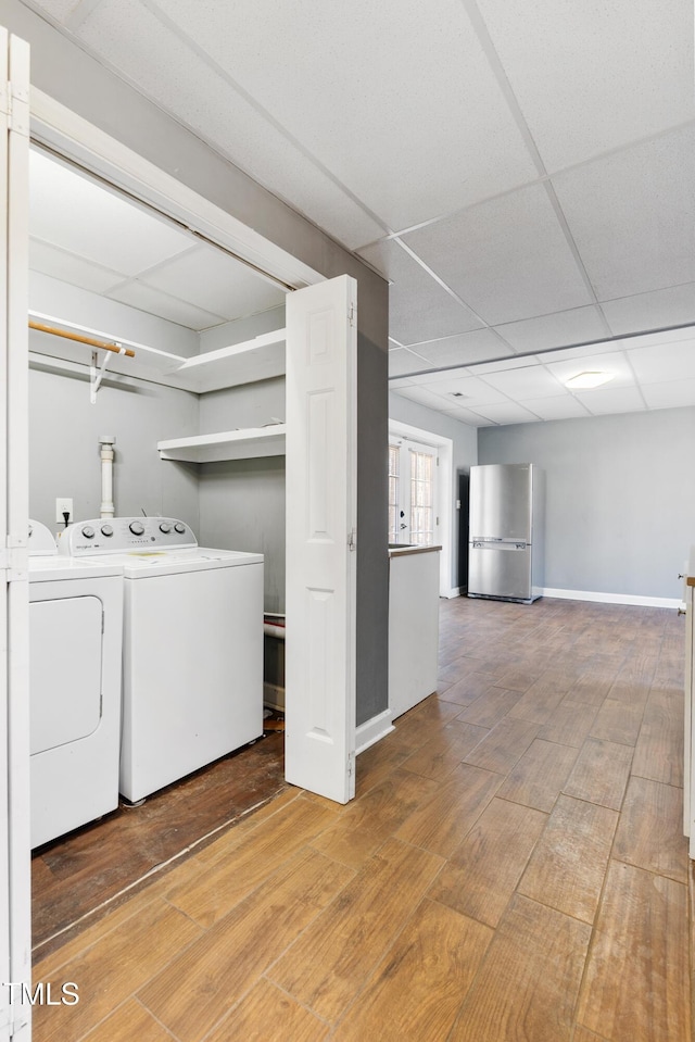 clothes washing area with laundry area, independent washer and dryer, wood finished floors, and baseboards