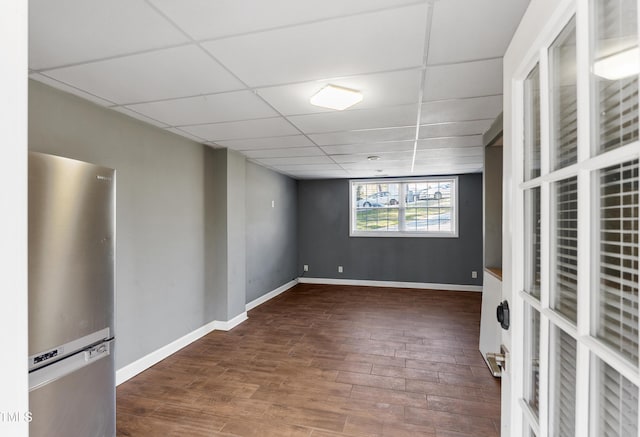 spare room featuring a drop ceiling, wood finished floors, and baseboards