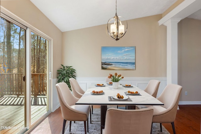 dining space featuring lofted ceiling, a notable chandelier, wood finished floors, and wainscoting