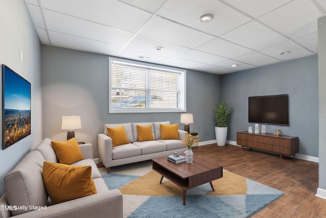 living room featuring baseboards, a drop ceiling, wood finished floors, and recessed lighting