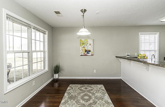 dining space featuring plenty of natural light, visible vents, and dark wood finished floors