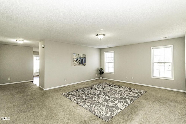 carpeted empty room with a textured ceiling and baseboards