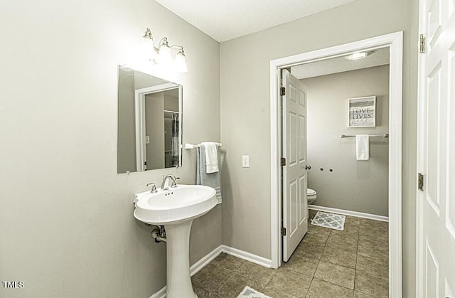 bathroom with toilet, baseboards, and tile patterned floors