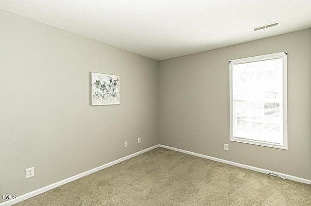 spare room featuring carpet, visible vents, and baseboards