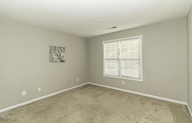 empty room featuring carpet floors, baseboards, visible vents, and a textured ceiling