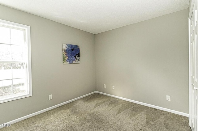 carpeted spare room featuring baseboards