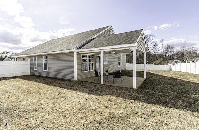 back of house featuring a patio area, a lawn, a fenced backyard, and roof with shingles