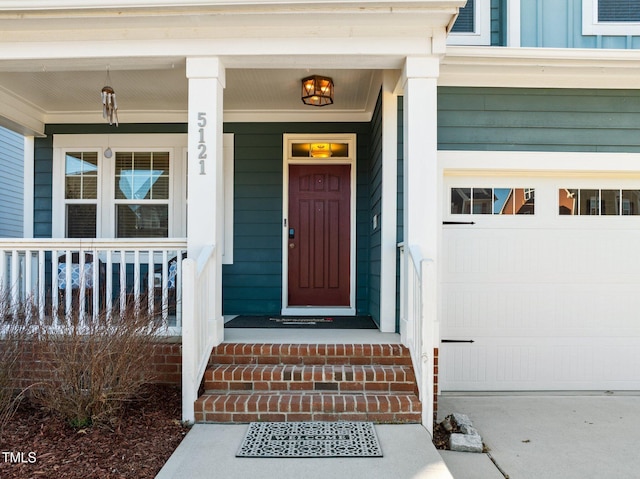 view of exterior entry with a porch, a garage, and board and batten siding