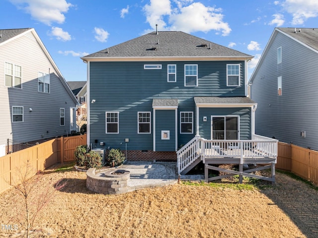 rear view of house featuring a deck, a fenced backyard, roof with shingles, and an outdoor fire pit