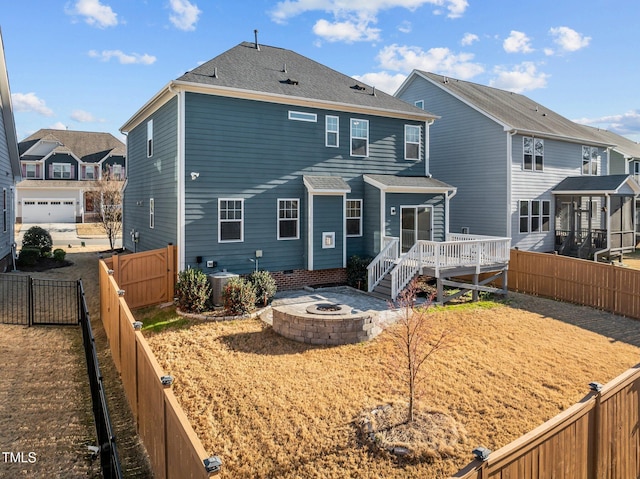 rear view of house with a fenced backyard, an outdoor fire pit, a shingled roof, a wooden deck, and central AC unit