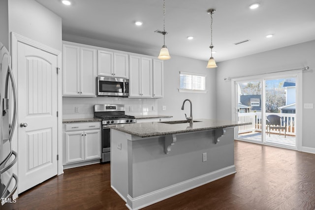 kitchen with visible vents, a sink, dark stone countertops, dark wood-style floors, and appliances with stainless steel finishes