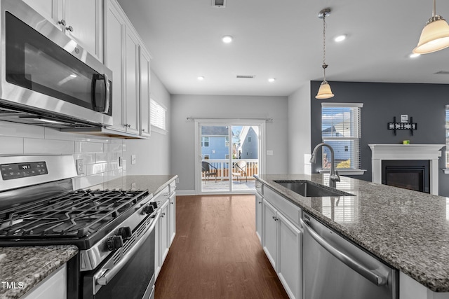 kitchen with visible vents, dark wood-type flooring, a sink, tasteful backsplash, and appliances with stainless steel finishes