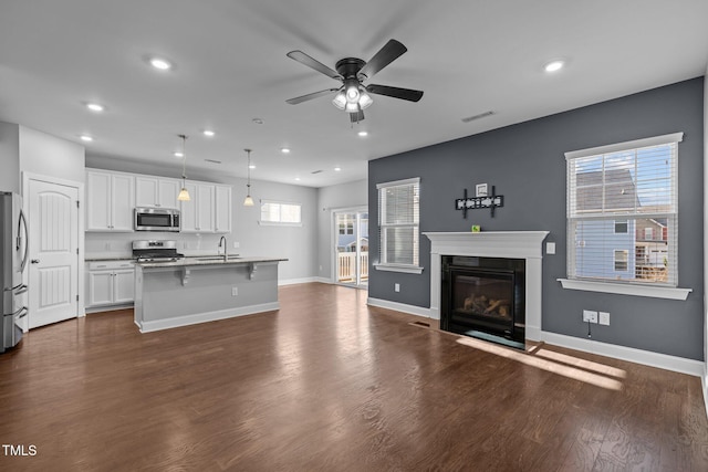 kitchen with dark wood-style floors, visible vents, stainless steel appliances, white cabinetry, and open floor plan