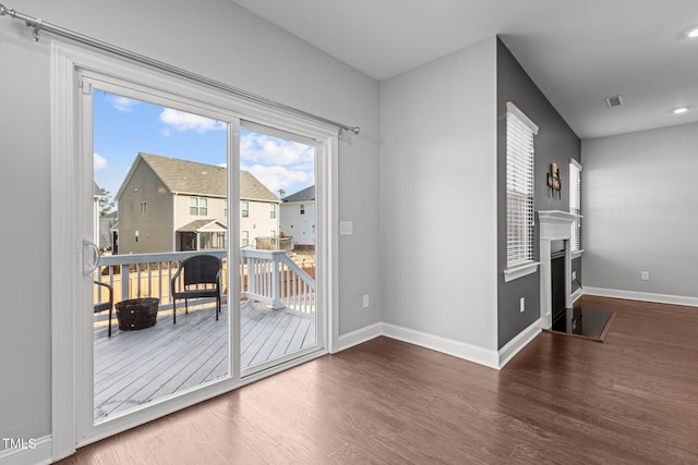 entryway featuring a fireplace with flush hearth, visible vents, baseboards, and wood finished floors