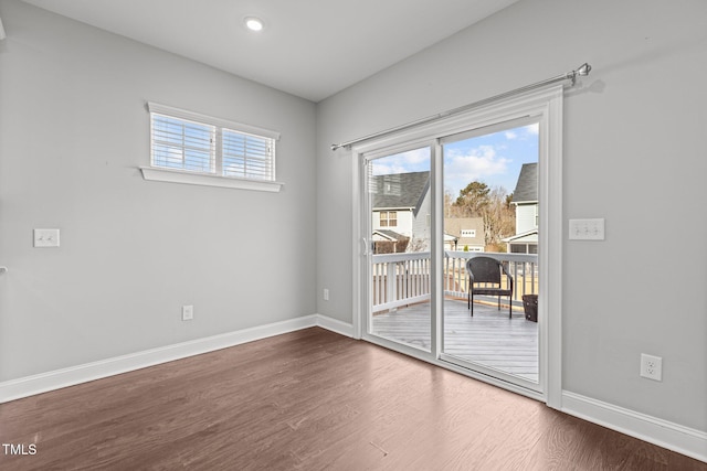 spare room featuring dark wood-type flooring, baseboards, and a wealth of natural light