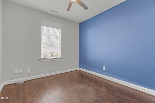 spare room with a ceiling fan, wood finished floors, visible vents, and baseboards