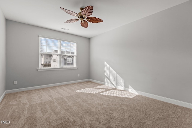 empty room featuring visible vents, light colored carpet, baseboards, and ceiling fan