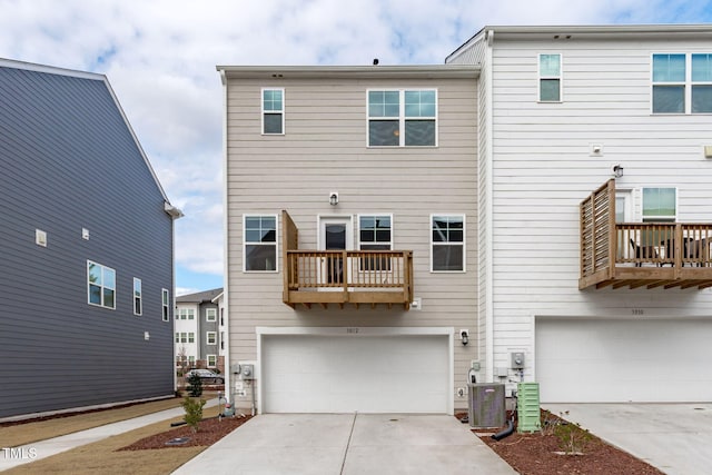 rear view of property with a garage, driveway, and a balcony