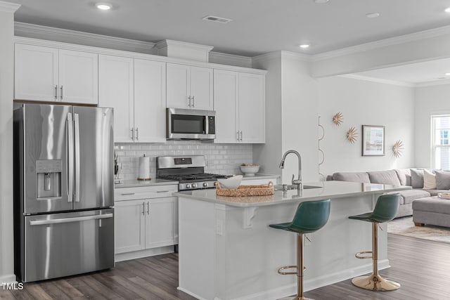 kitchen featuring a breakfast bar area, visible vents, appliances with stainless steel finishes, dark wood-type flooring, and open floor plan