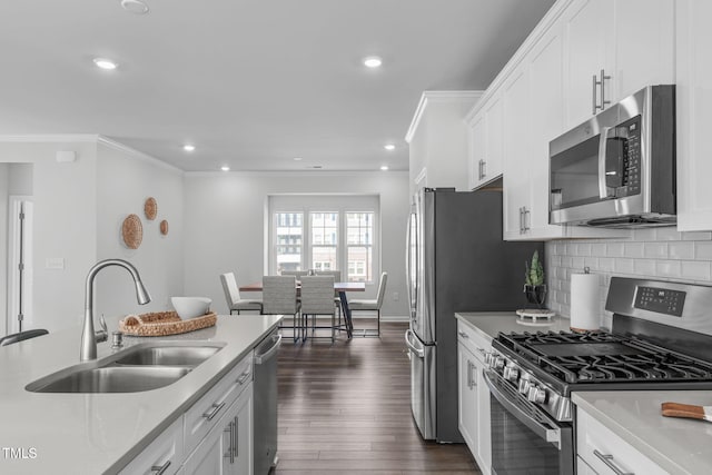 kitchen featuring stainless steel appliances, crown molding, a sink, and white cabinetry