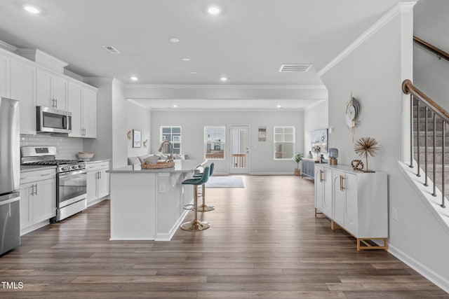 kitchen with stainless steel appliances, visible vents, decorative backsplash, open floor plan, and white cabinetry