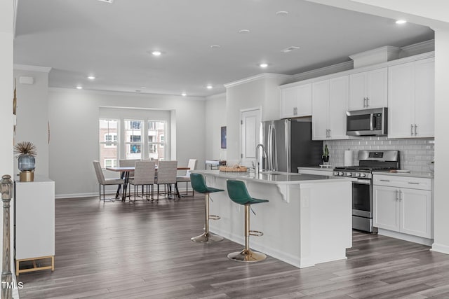 kitchen featuring stainless steel appliances, a kitchen island with sink, dark wood finished floors, and decorative backsplash