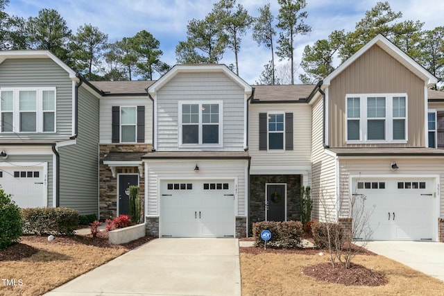 view of front of property featuring driveway, stone siding, and a garage