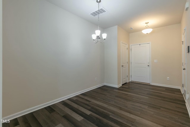 unfurnished dining area with dark wood-style floors, an inviting chandelier, visible vents, and baseboards