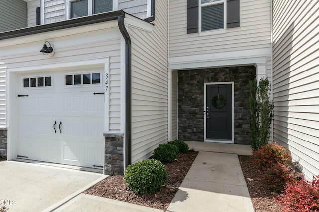 doorway to property featuring a garage and stone siding