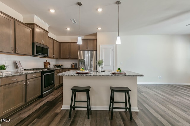 kitchen featuring visible vents, a breakfast bar area, appliances with stainless steel finishes, light stone counters, and backsplash