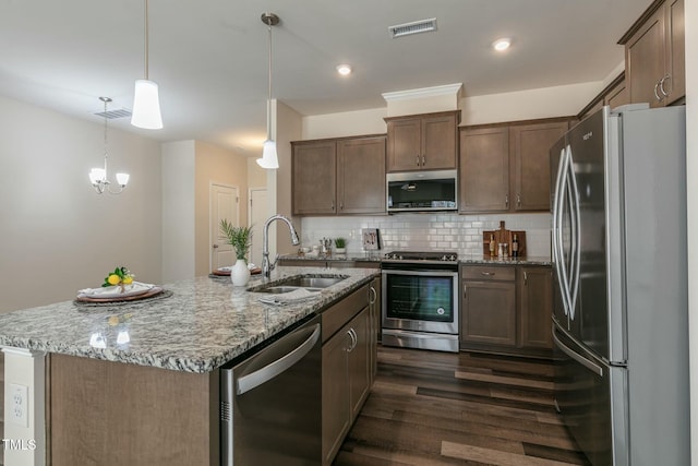 kitchen featuring light stone counters, visible vents, decorative backsplash, appliances with stainless steel finishes, and a sink