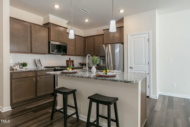 kitchen with visible vents, light stone counters, dark wood-type flooring, stainless steel appliances, and backsplash