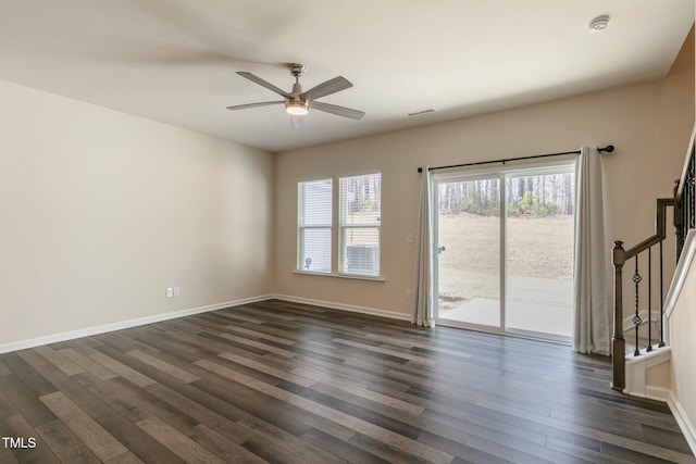 empty room featuring dark wood-style flooring, stairway, and baseboards