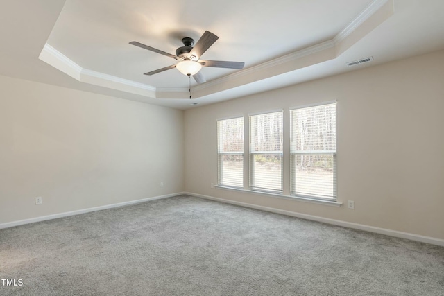 spare room featuring carpet floors, a raised ceiling, visible vents, and crown molding