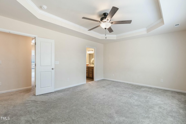 unfurnished bedroom featuring ornamental molding, carpet floors, a tray ceiling, and baseboards