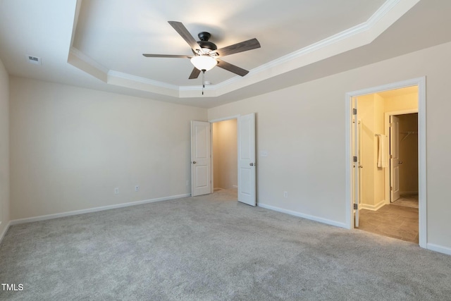 unfurnished bedroom with carpet flooring, visible vents, baseboards, a tray ceiling, and crown molding