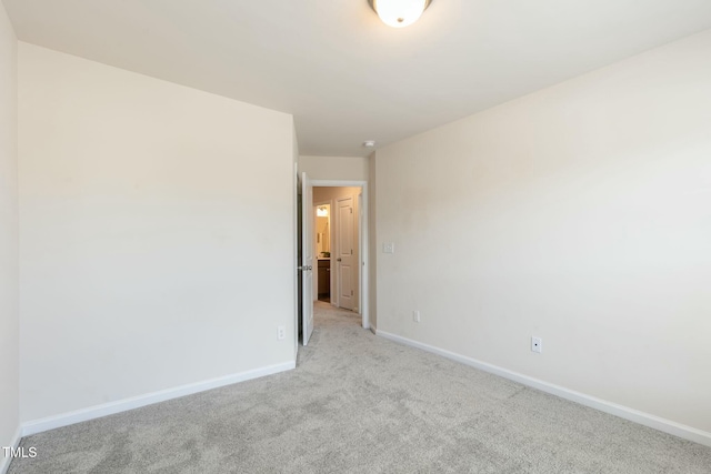 spare room with baseboards and light colored carpet