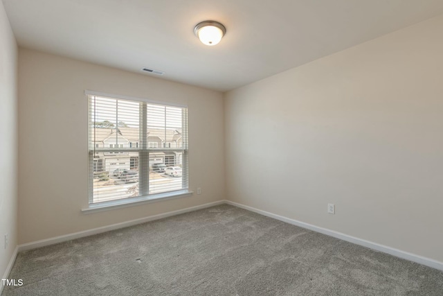 spare room with carpet floors, visible vents, and baseboards