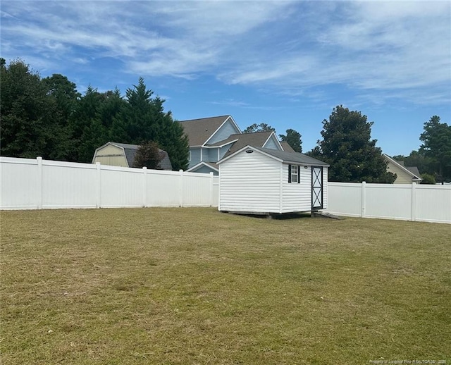 view of yard with a fenced backyard, a shed, and an outbuilding