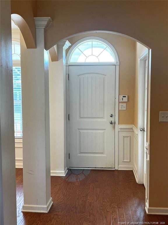 entryway featuring dark wood-style floors, arched walkways, and a decorative wall