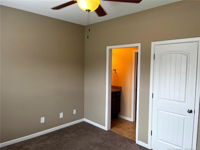 unfurnished bedroom featuring dark carpet, dark tile patterned floors, baseboards, and ceiling fan