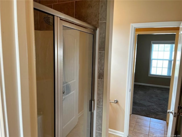 full bath with a stall shower, tile patterned flooring, and baseboards