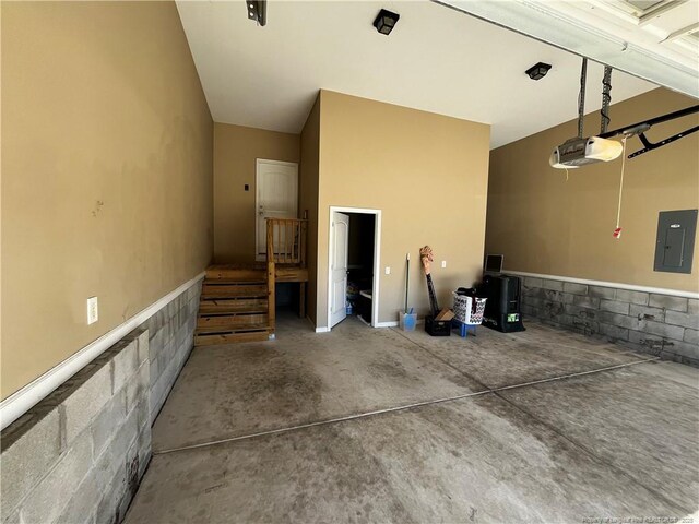 garage featuring concrete block wall, electric panel, and a garage door opener