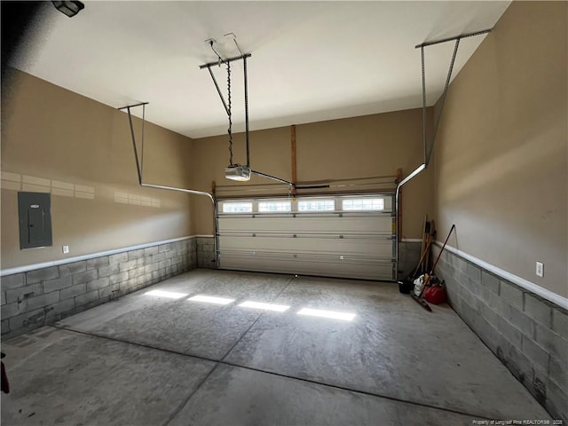 garage with concrete block wall, electric panel, and a garage door opener