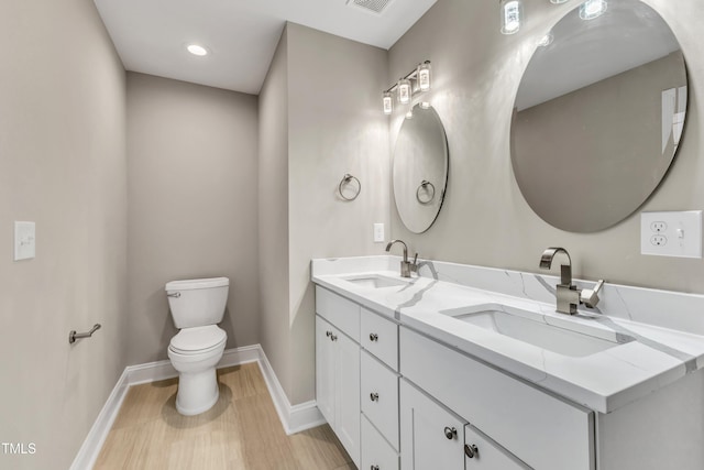 bathroom featuring double vanity, a sink, toilet, and baseboards