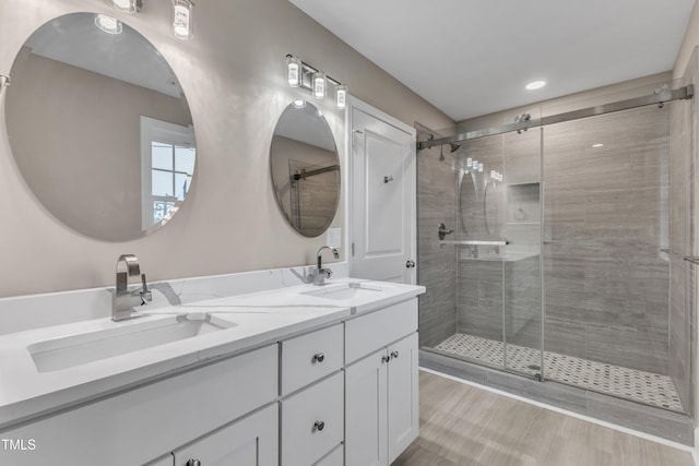 bathroom featuring double vanity, a shower stall, and a sink